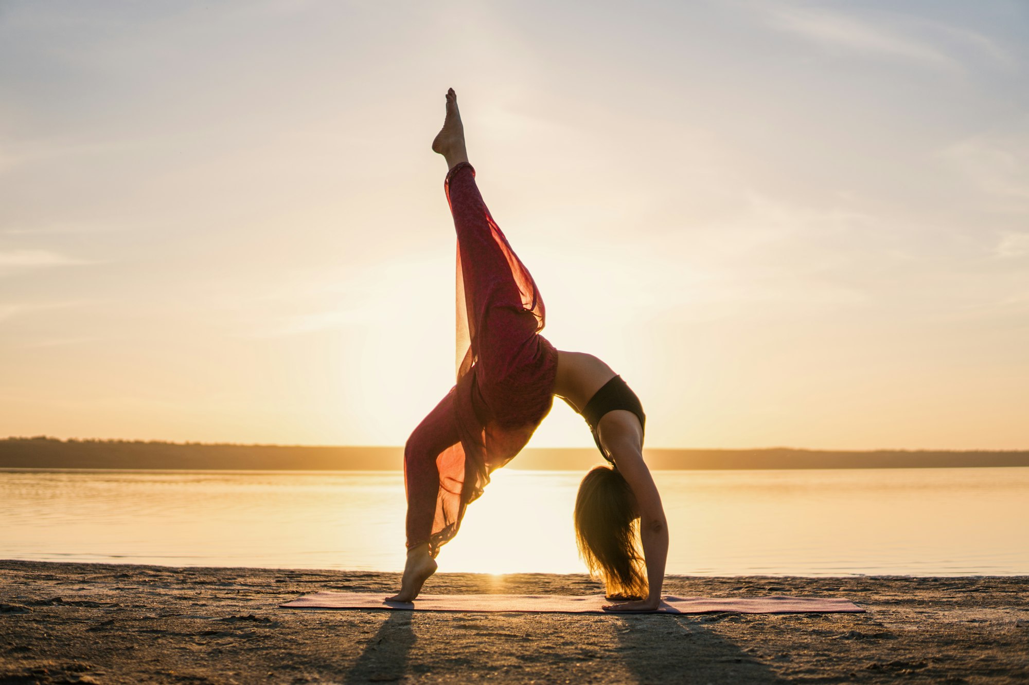 silhouette-yoga-woman-on-the-beach-at-sunset-X4XUD9G